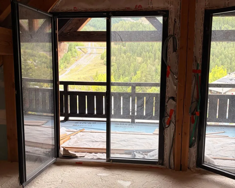 Sol isolé devant une grande baie sous charpente — chantier à Auron